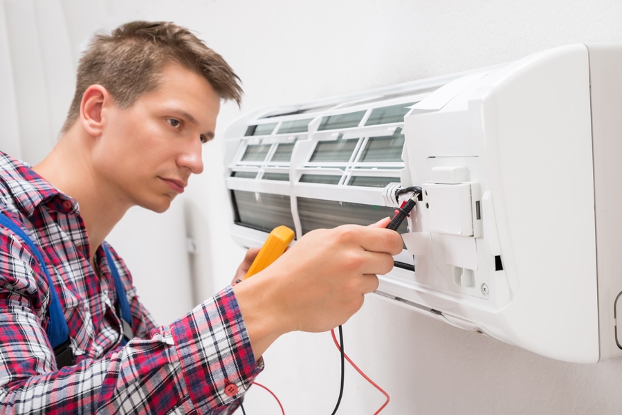Male Technician Examining Air Conditioner With Multimeter. What you need to know for a HVAC emergency.