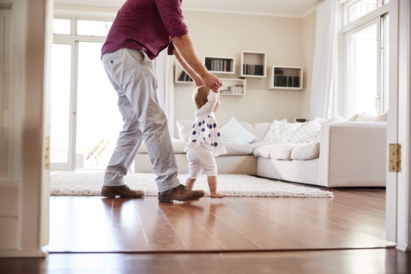 Father helping daughter learn to walk at home, side view. What is IAQ important?.